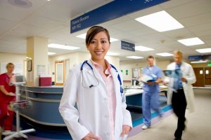 Health professional in hospital hallway smiling at camera